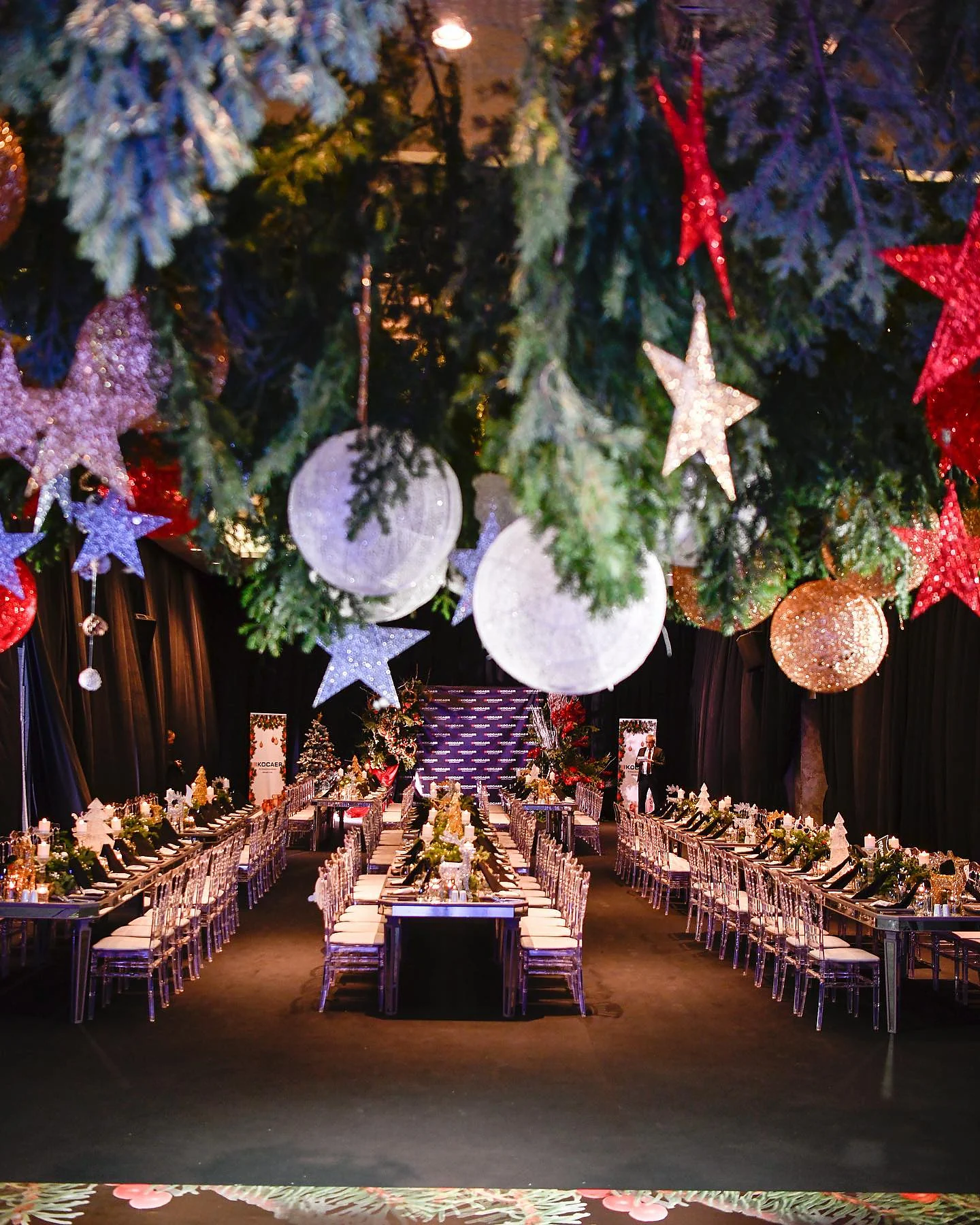 Christmas Gala: Salonun geniş görünümü: tavandan sarkan çam dalları, yıldızlar ve beyaz küreler