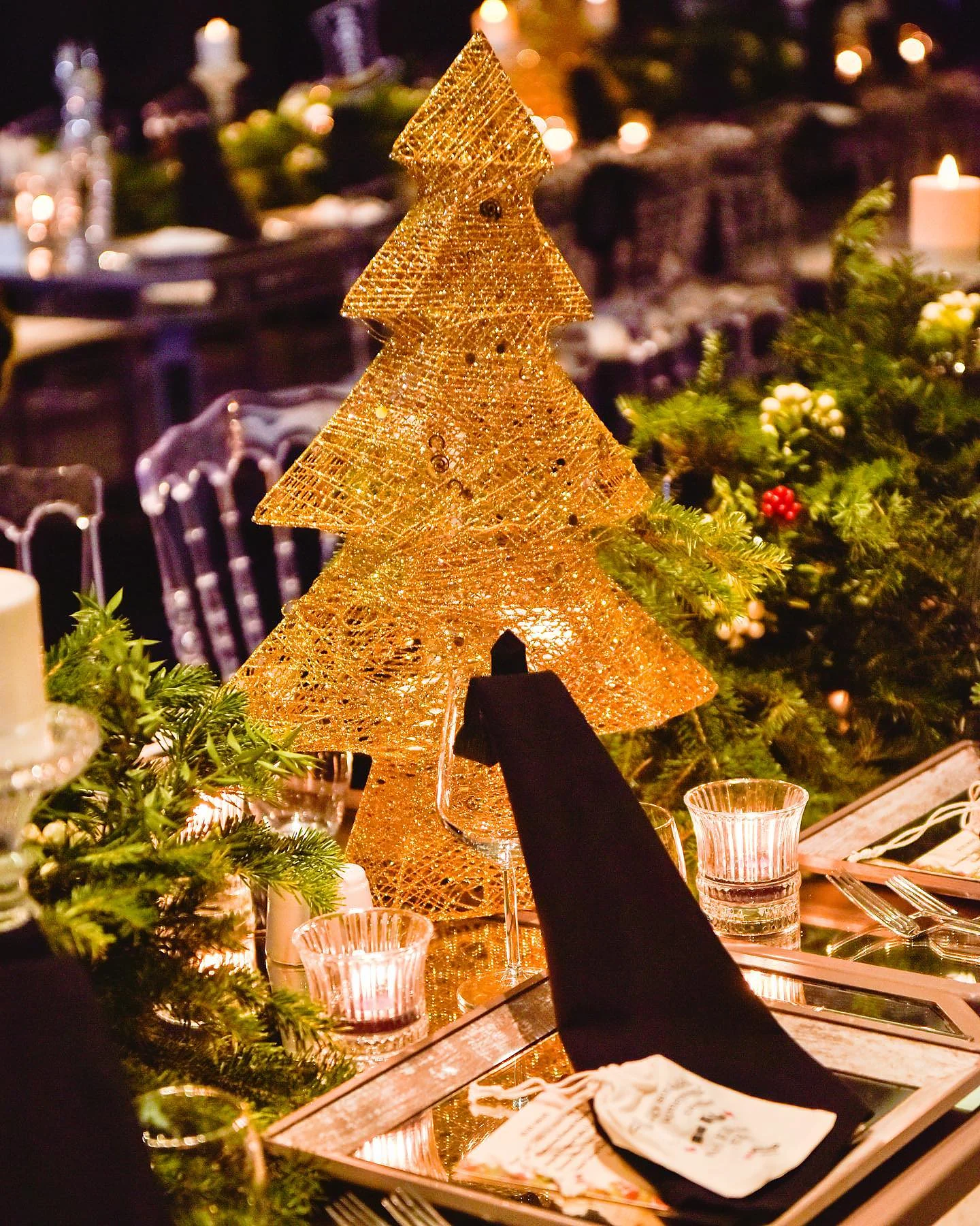 Christmas Gala: Altın tel yılbaşı ağacı figürü; yeşillik, mumlar ve siyah peçeteler