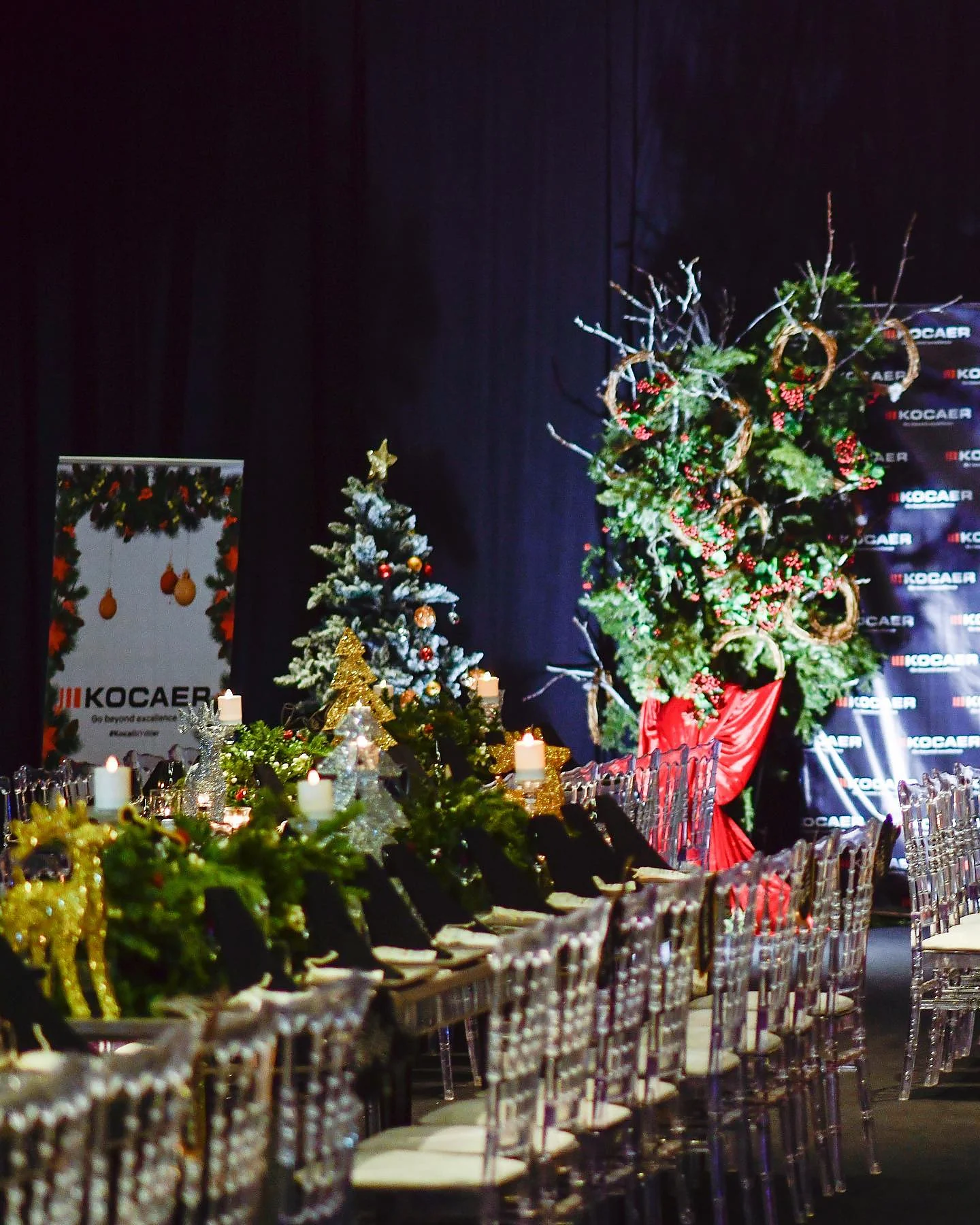 Christmas Gala: Salonun uzun ekseninde yılbaşı ağaçları ve yeşillik sütunlarıyla kurulan masa dizisi