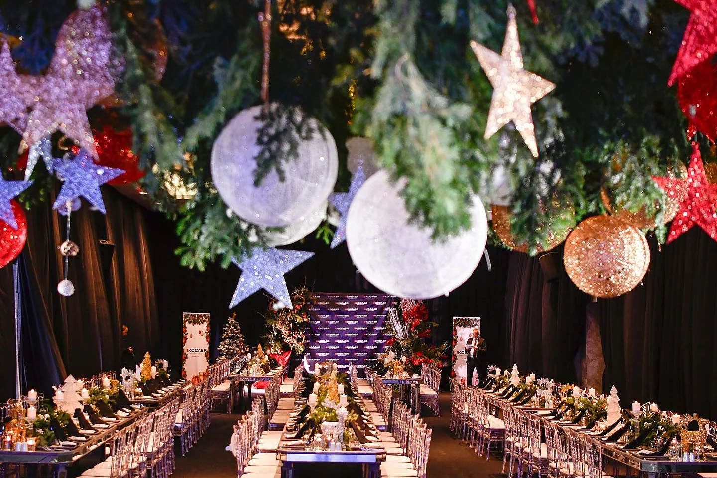 Christmas Gala: Salonun geniş görünümü: tavandan sarkan çam dalları, yıldızlar ve beyaz küreler
